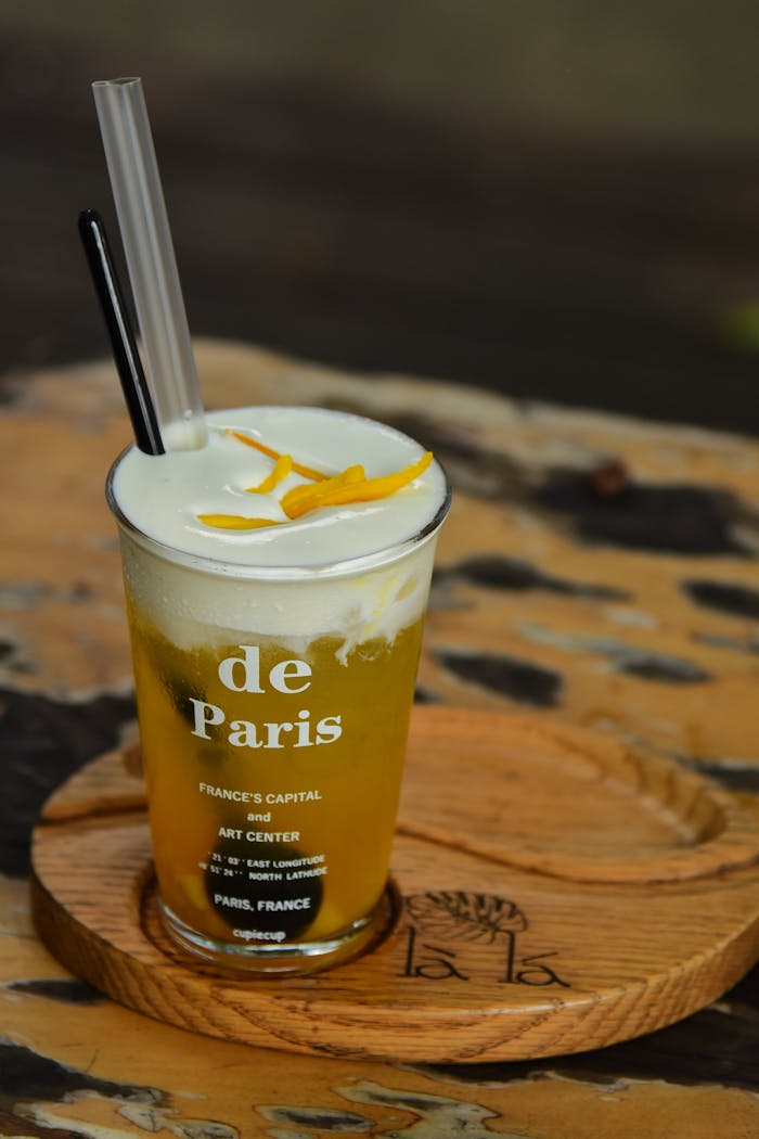 services-01 A delicious citrus drink in a trendy Paris-themed glass on a rustic wooden table.