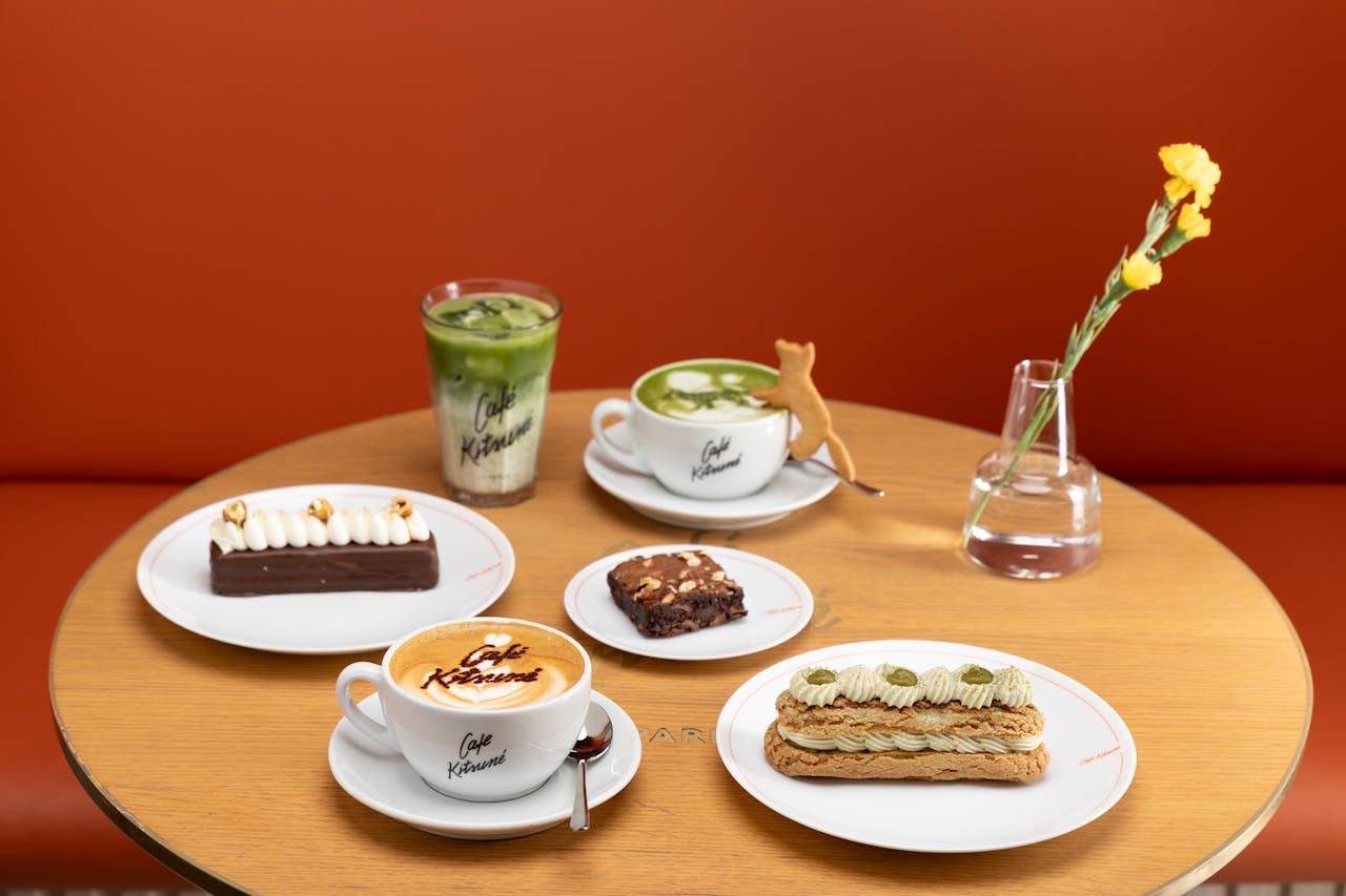 gallery-6 A stylish café table featuring a variety of desserts, drinks, and a flower vase.